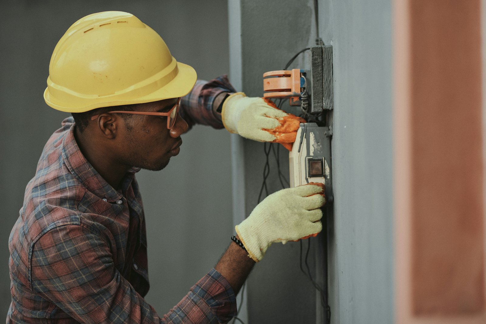 Handwerker montiert eine technische Installation an einer Gebäudewand